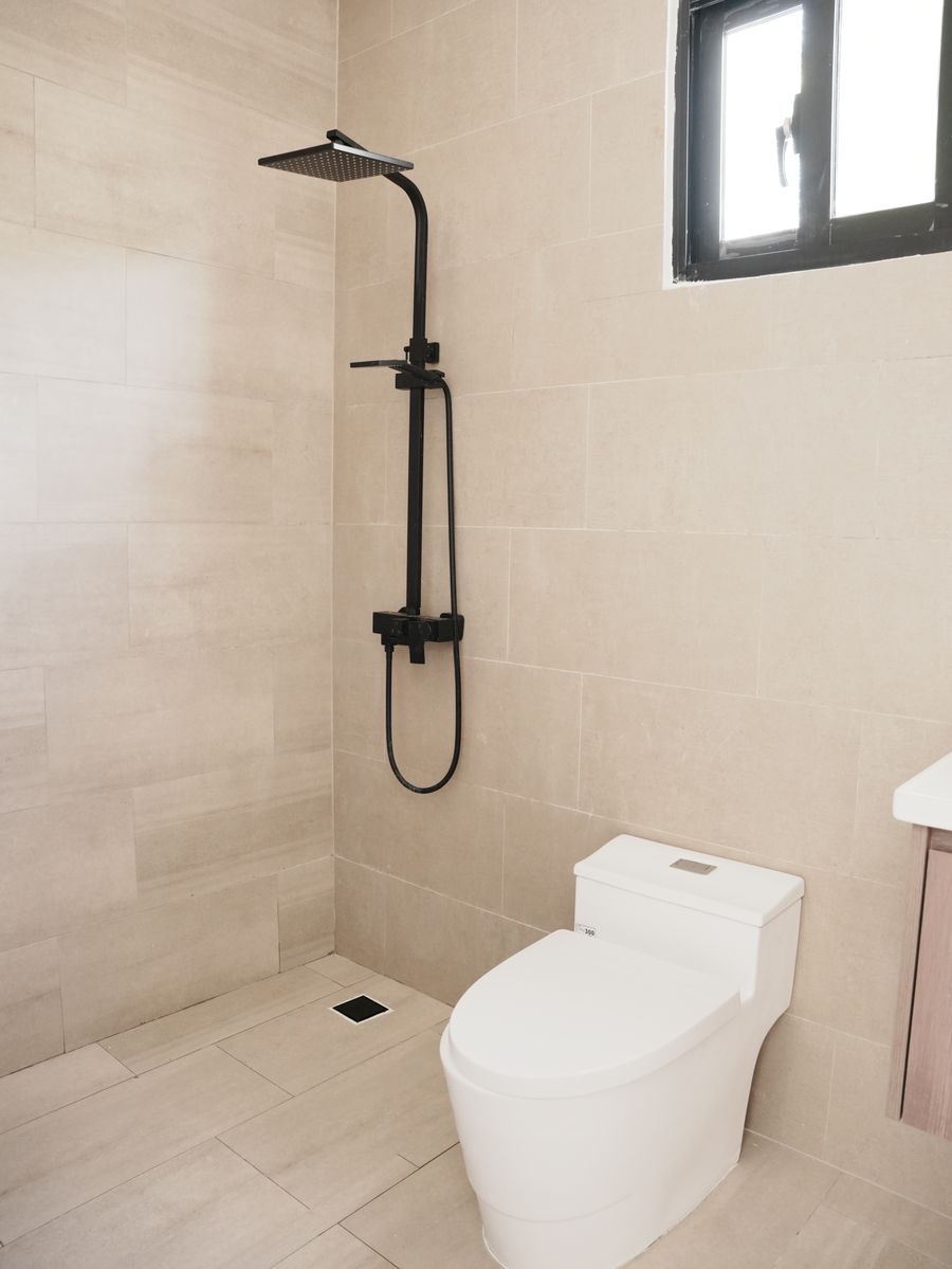 Villas Waves en Bávaro: baño terminado con ducha de lluvia negra mate, revestimiento beige e inodoro de una pieza
