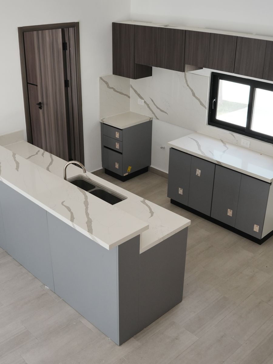 Villas Waves en Bávaro: cocina terminada con isla de cuarzo blanco y gabinetes grises y de madera oscura