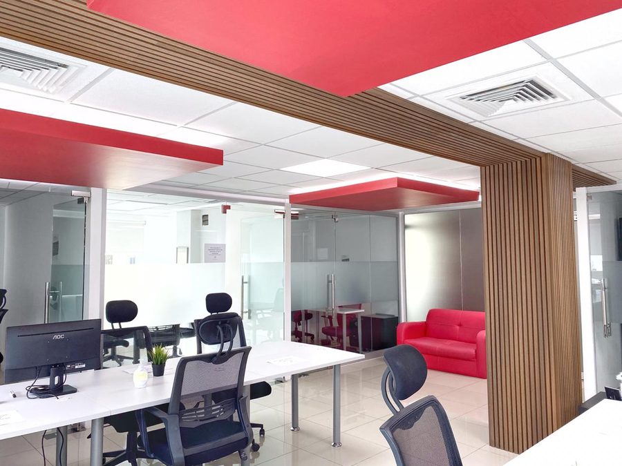 Interior de oficina moderna con columna de listones de madera, mamparas de cristal y plafones rojos