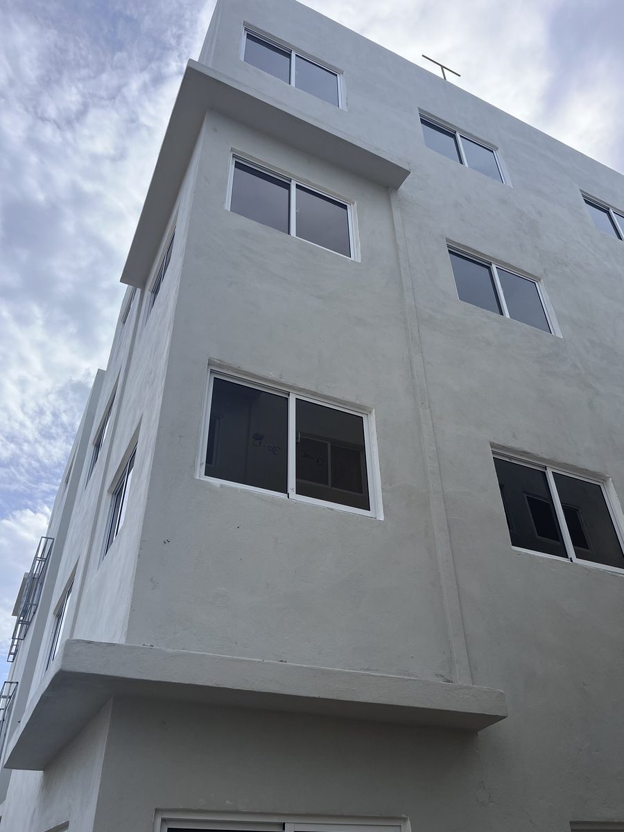 Esquina de edificio blanco con ventanas de aluminio y voladizo de hormigón en el proyecto Trapiche